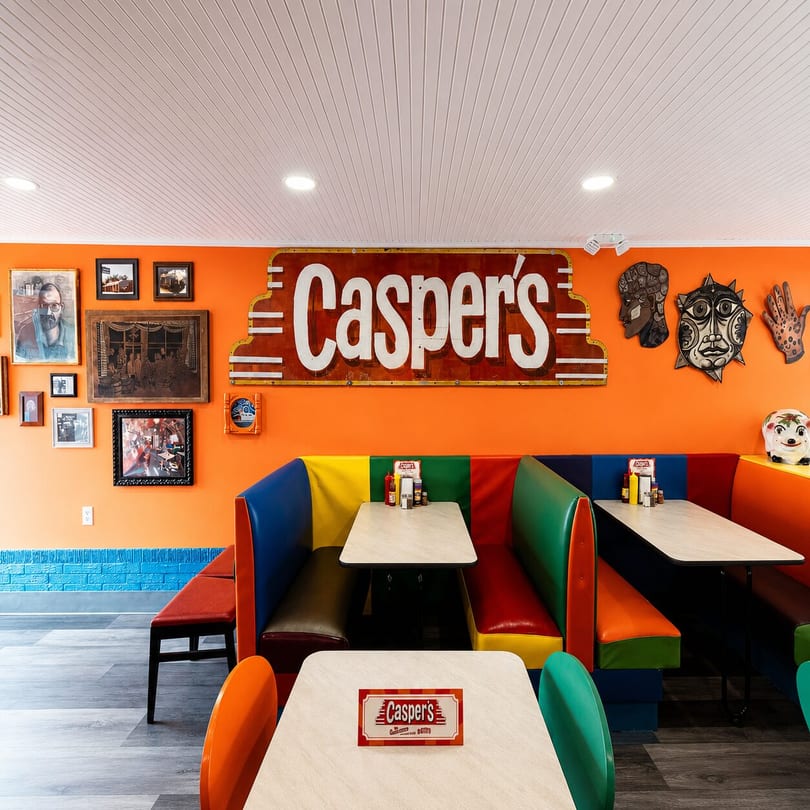 Casper's restaurant interior with orange walls, colorful booths, and a large "Casper's" sign.