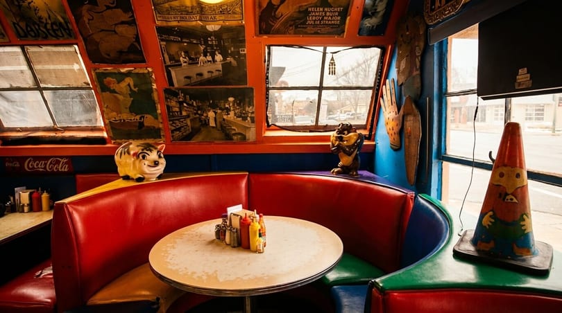 A colorful diner booth with red and blue seating, a round table, and vintage decor.